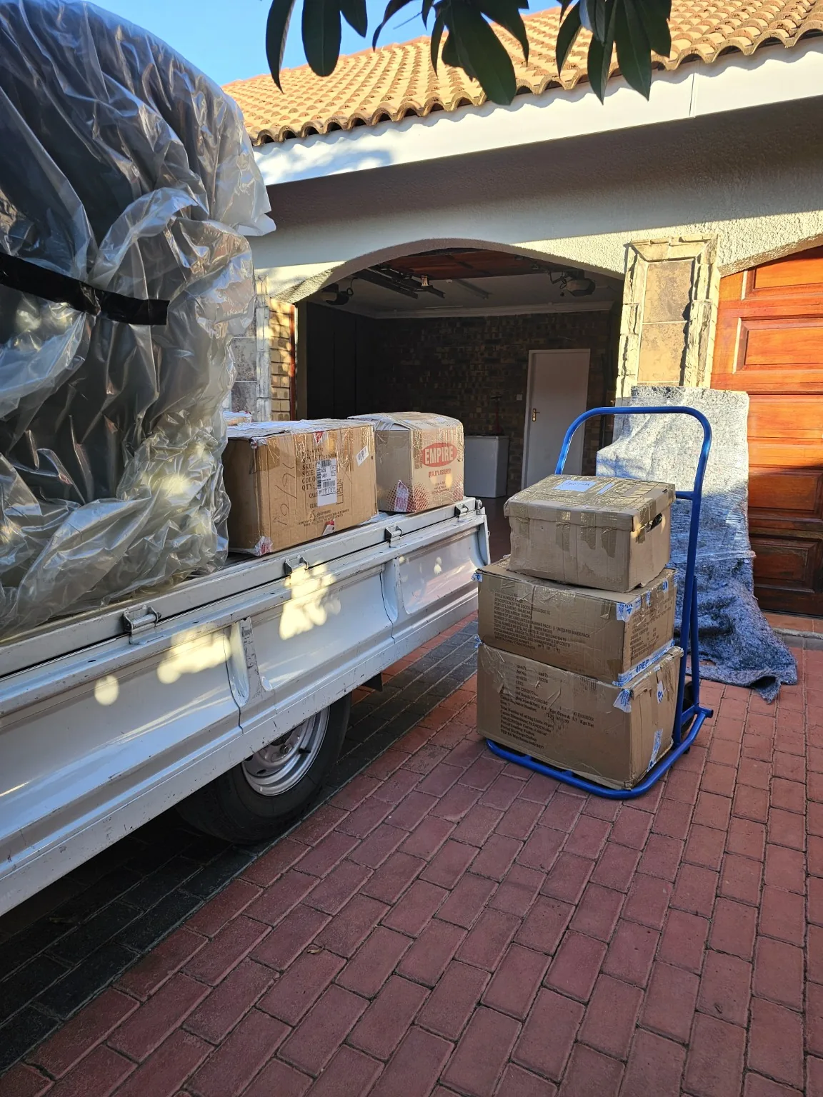 Moving boxes and wrapped items prepared beside a trailer